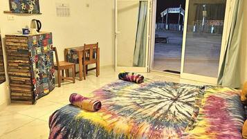 A room with a bed, a desk, a chair, a window with curtains, and a wall-mounted air conditioner.