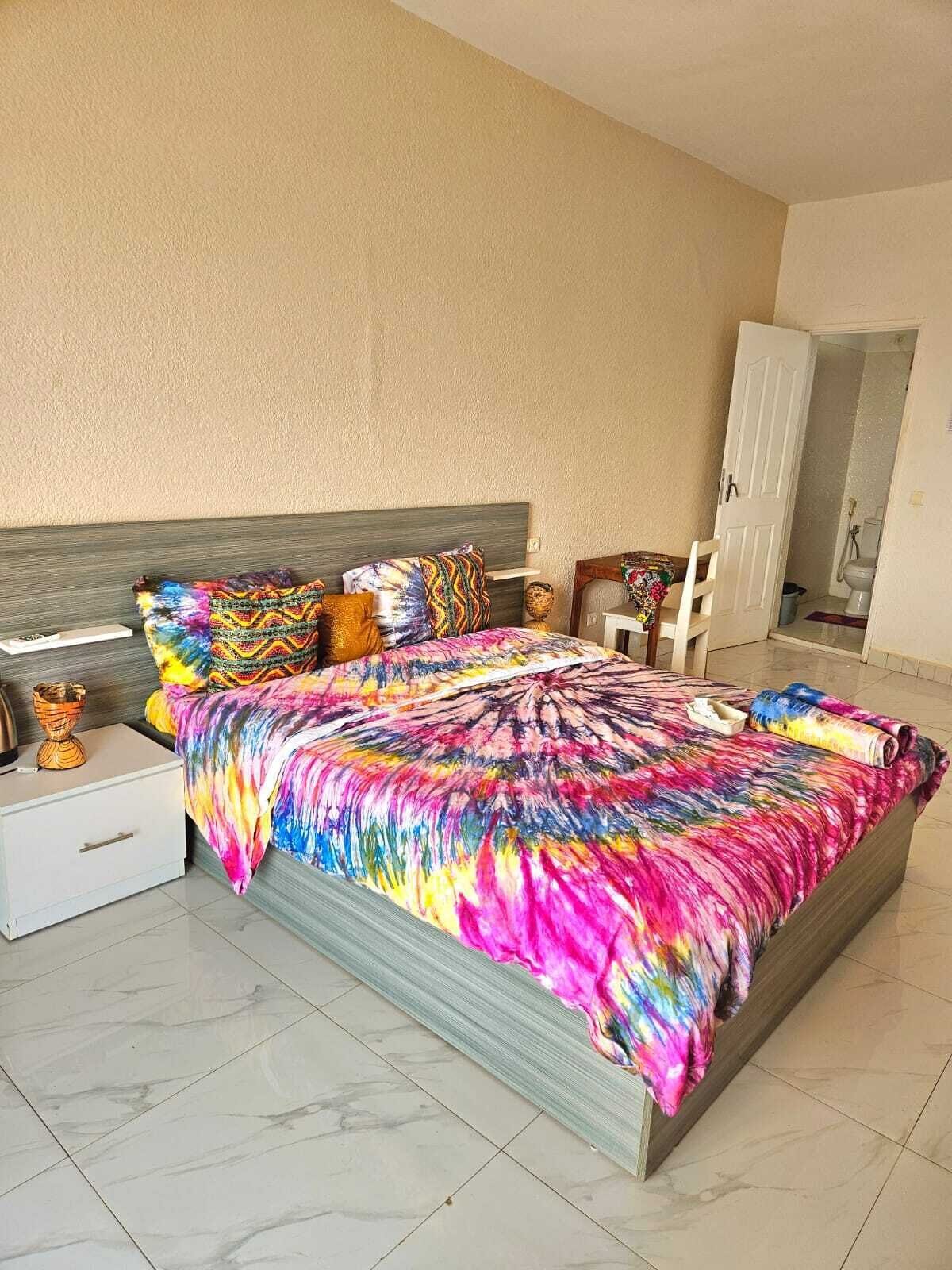 A bedroom with a bed, nightstands, a chair, and a door leading to a bathroom.