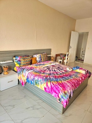 A bedroom with a bed, nightstands, a chair, and a door leading to a bathroom.