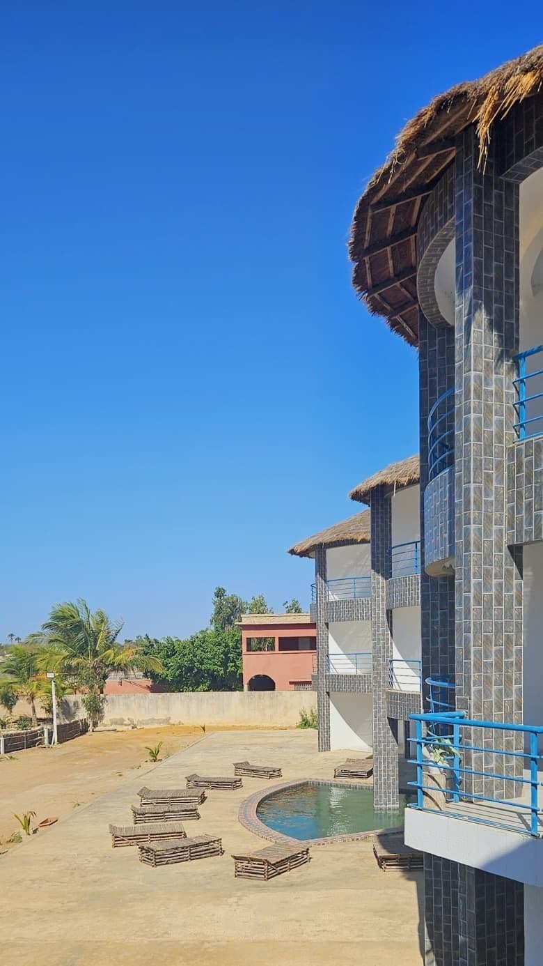 Un hôtel doté d’une piscine, d’un espace extérieur aménagé et surplombant un ciel d’un bleu limpide.