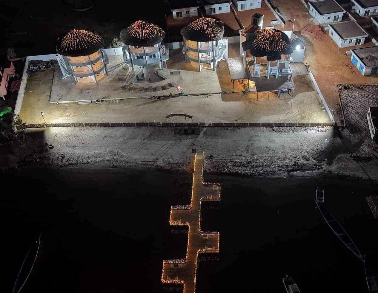 Una proprietà sul lungomare con tre strutture illuminate, un molo e una barca.