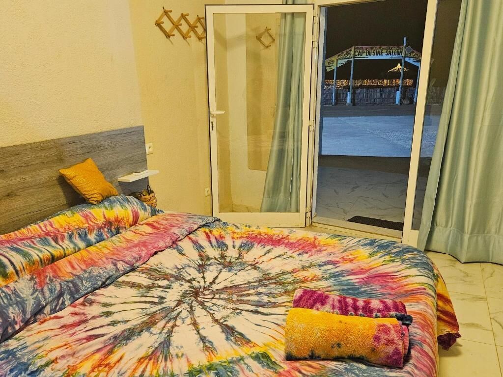 Une chambre d’hôtel avec un lit, une table de chevet, une fenêtre avec des rideaux et une vue sur un bâtiment à l’extérieur.