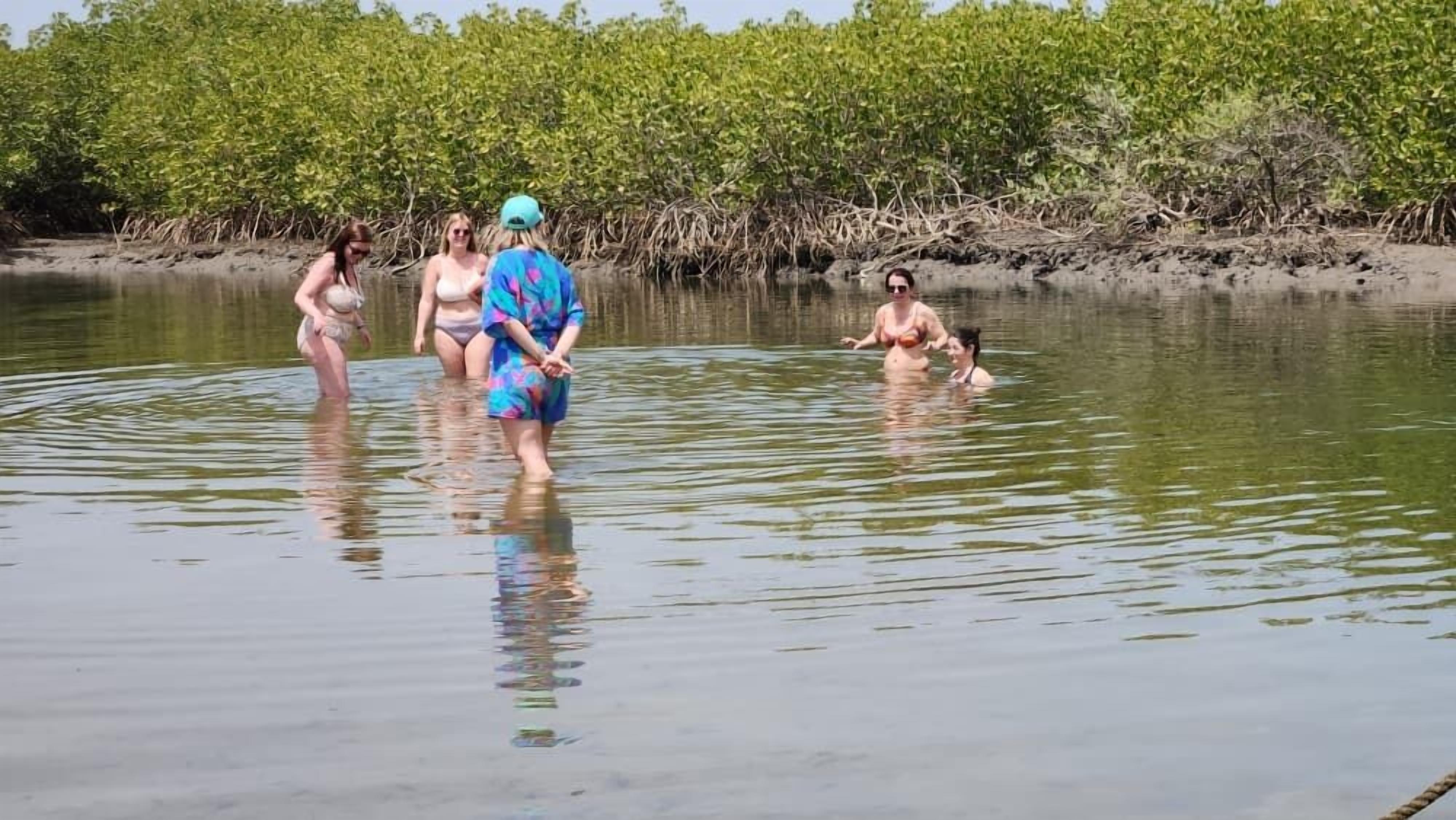 Un grupo de personas en un entorno acuático natural con vegetación densa al fondo.