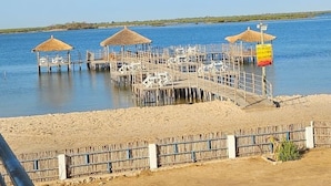 A pier with thatched-roof structures and a sandy beach area.