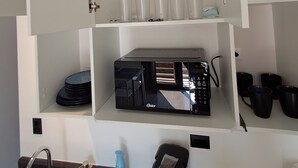 Een keuken met een magnetron, koffiezetapparaat en diverse keukengerei.
