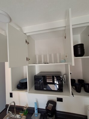 Una cocina equipada con microondas, cafetera y diferentes utensilios de cocina.