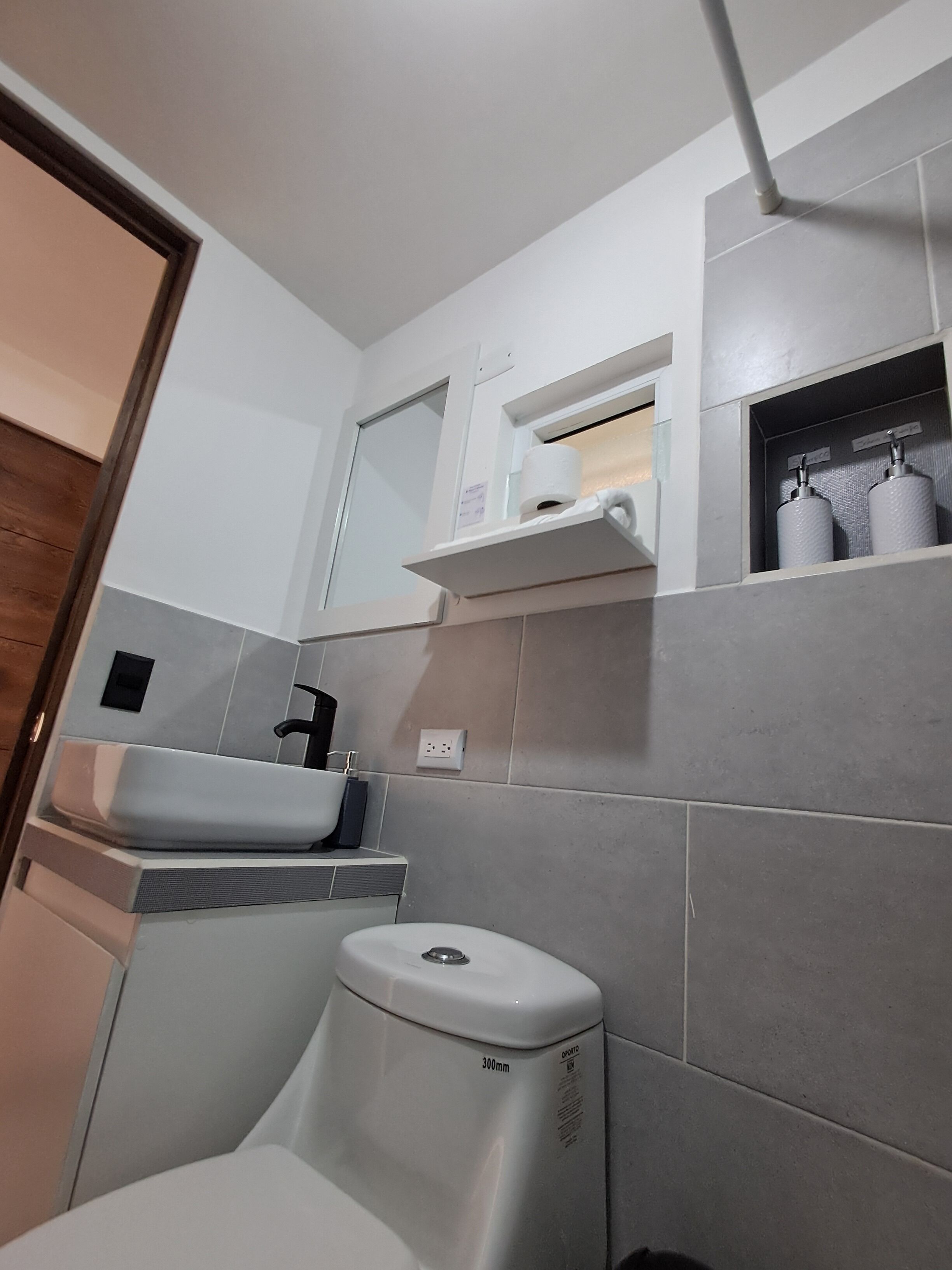 A modern bathroom with a toilet, sink, and towel dispenser.