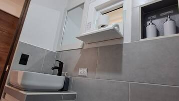 A modern bathroom with a toilet, sink, and towel dispenser.