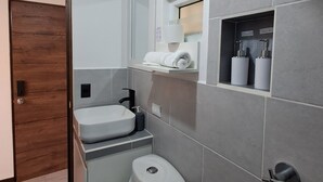 Une salle de bain moderne équipée de toilettes, d’un lavabo et d’un porte-serviettes.