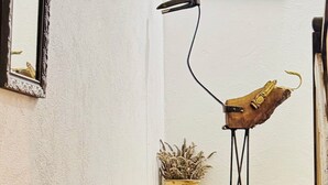 A room with a framed mirror, a blue abstract painting, a unique wooden sculpture, and a potted plant. - Roquepoix - A green stopover in the Gers (Mirepoix)