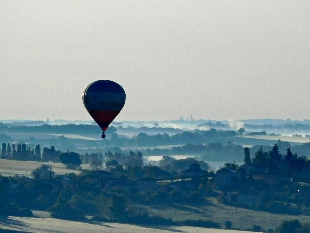 Eine Heißluftballonfahrt über einer Landschaft mit Feldern und Bäumen.
