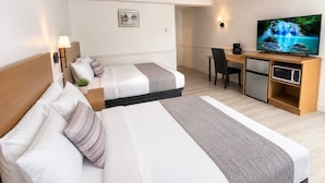 A hotel room with two beds, a desk, a television, and a microwave. - Tumbleweed Motel  (Cache Creek)