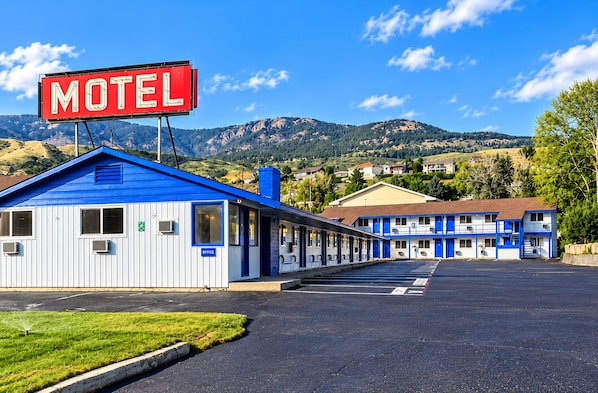 Un motel reconnaissable à son grand panneau rouge, à sa façade bleue et blanche et à son parking.