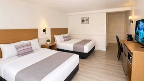 A hotel room with two beds, a desk, a television, and a small plant. - Tumbleweed Motel  (Cache Creek)