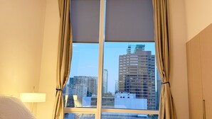 Une chambre d’hôtel avec un lit, une fenêtre avec des rideaux et une vue sur les bâtiments de la ville.