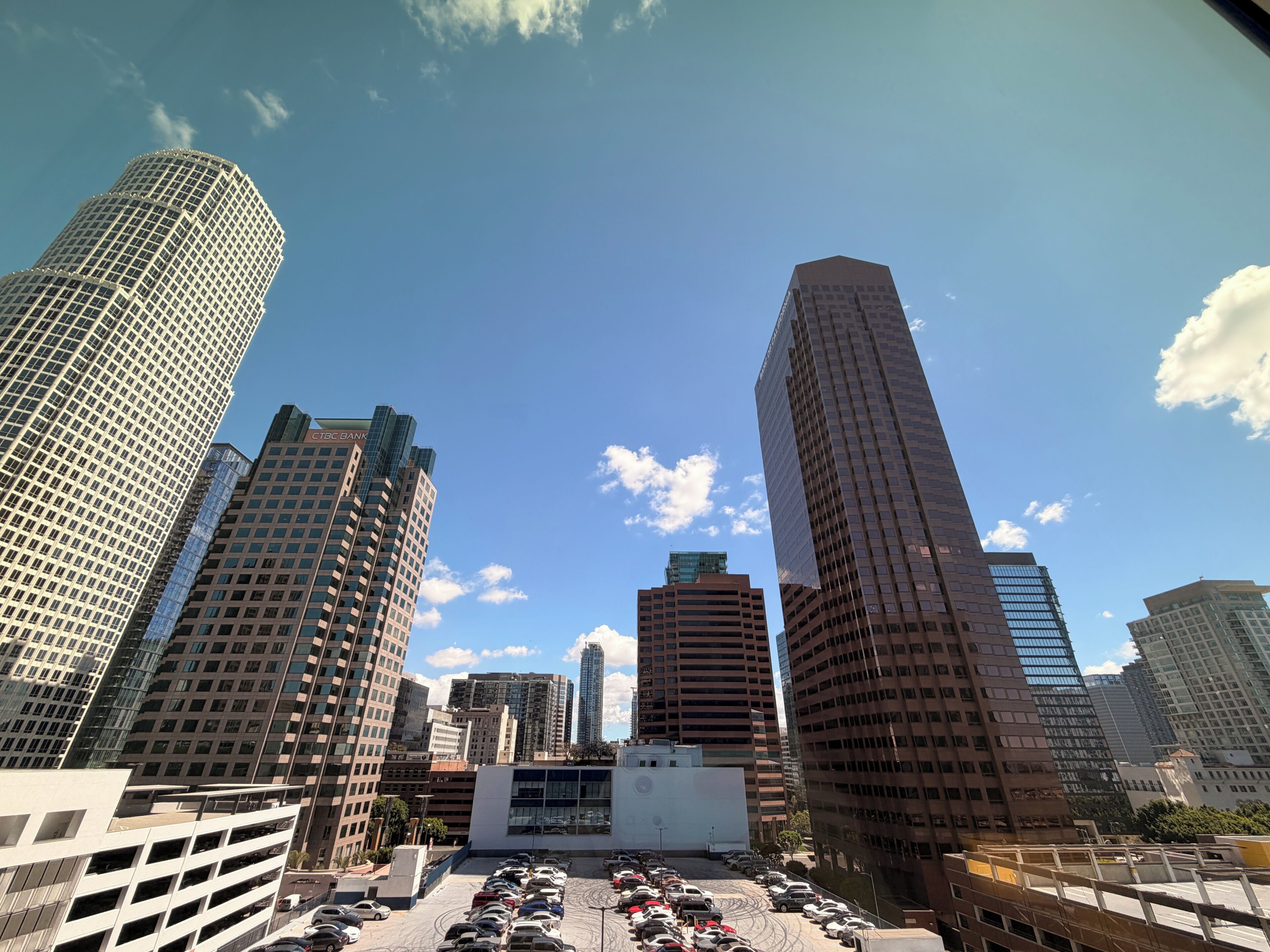 A cityscape with tall buildings, a parking lot, and a clear sky.