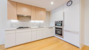 Une cuisine moderne avec des armoires blanches, un four encastré et une horloge au mur.
