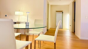 Un espace repas moderne avec une table en verre, des chaises blanches et un lampadaire.