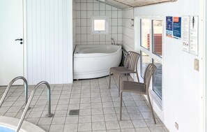 A bathroom with a bathtub, a shower, a window, and a chair. - Beautiful home in Lemvig with sauna (Lemvig)