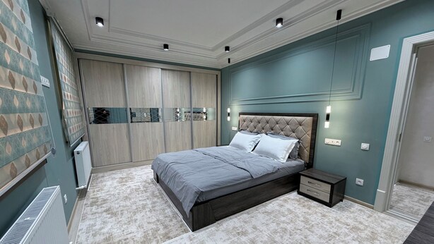 Un dormitorio con cama, mesita de noche, armario y radiador.