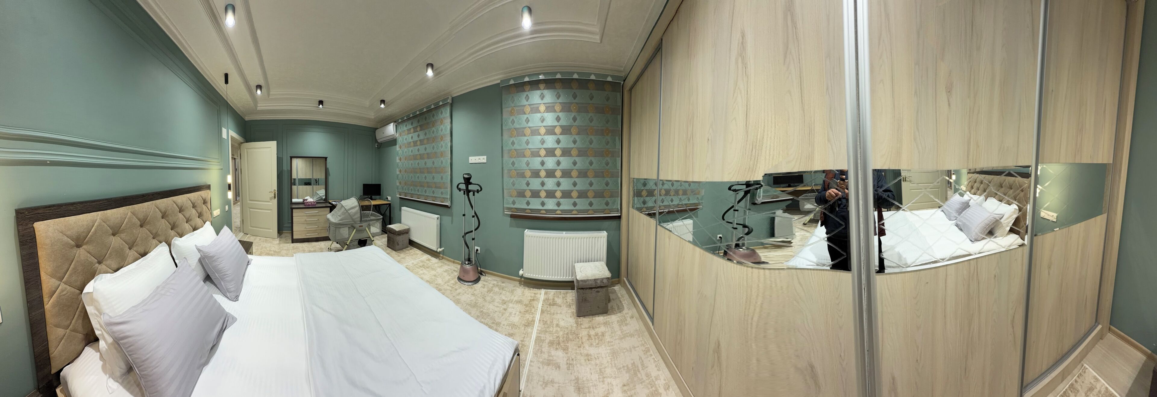 A hotel room with a large bed, a vanity with a mirror, a desk, and a chair.