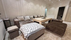 Un dormitorio moderno con una cama grande, un sofá, una mesita de café y una pequeña mesa con un ordenador portátil.