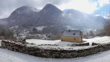 A snow-covered landscape with a stone wall and a yellow building.