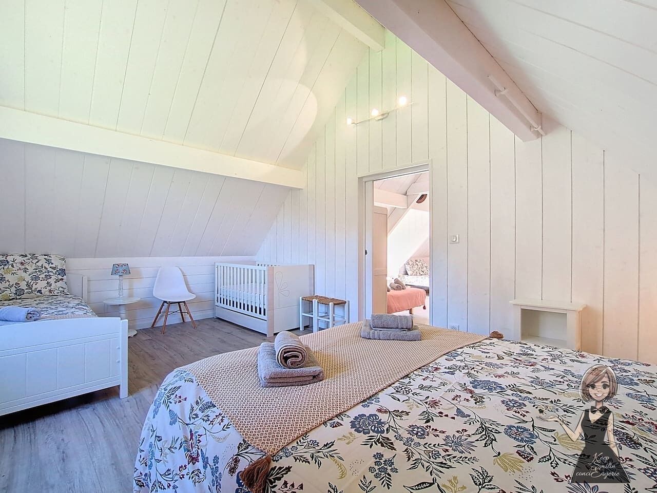 A bedroom with a bed, a chair, a small table, and a crib.