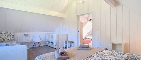 A bedroom with a bed, a chair, a small table, and a crib.
