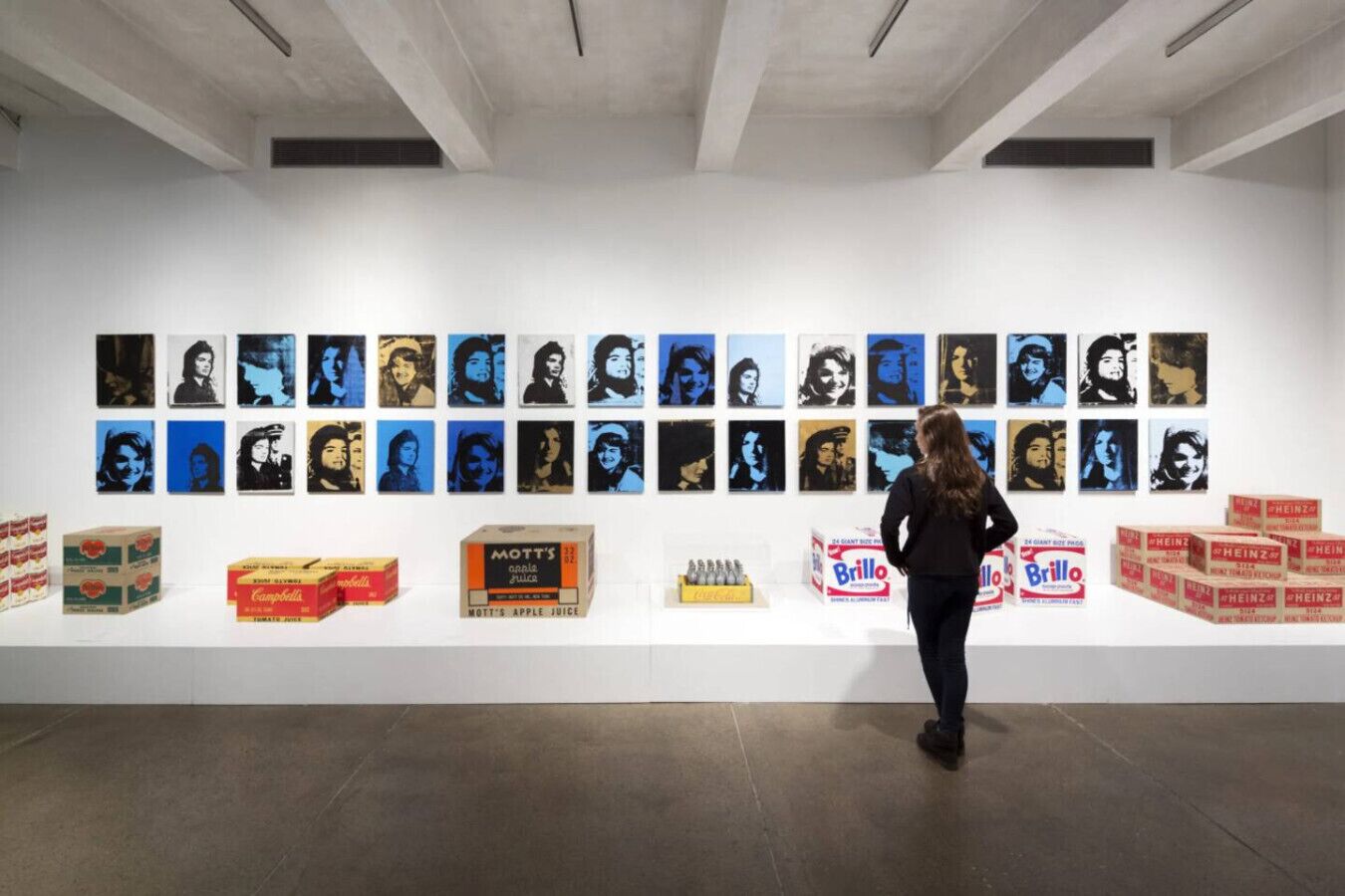 A gallery with artworks on the wall and boxes of products on the floor.