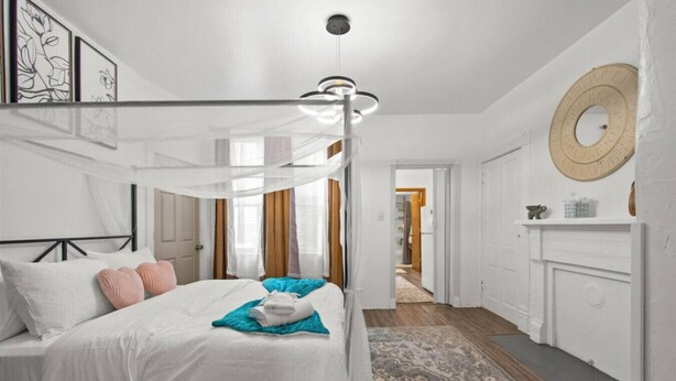 A bedroom with a canopy bed, a fireplace, and a hallway leading to another room. - Double Living, Patio BBQ, Massage & South Side Fun (Pittsburgh)
