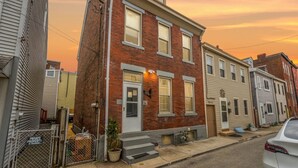 A row of brick townhouses with a small front porch, a potted plant, and a private property sign. - Double Living, Patio BBQ, Massage & South Side Fun (Pittsburgh)