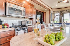 A kitchen with stainless steel appliances, wooden cabinets, a marble countertop, and a view of the outdoors. - Sandbridge Luxury RV Resort - Beach - Pool - Grill (Virginia Beach)