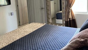 A bedroom with a bed, a ceiling fan, an air conditioning unit, a TV, and a window with curtains. - Spacious 3-bedroom apartment in perfect Barranquilla with AC (Barranquilla)