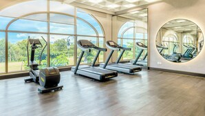 Ein Fitnessstudio mit Laufbändern, Crosstrainern und einem großen Spiegel.
