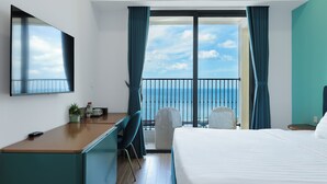 Ein Hotelzimmer mit Balkon, Schreibtisch, Stuhl, Bett und Fernseher.