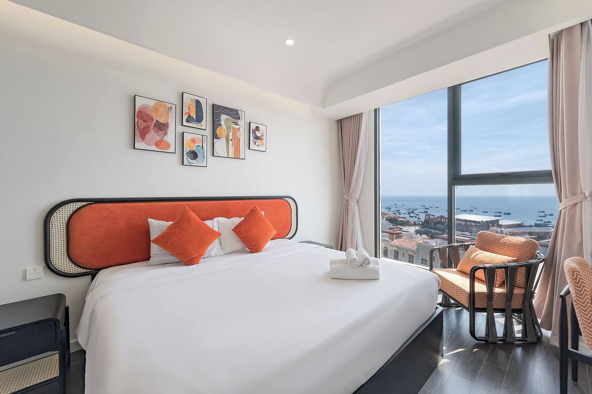 Habitación de hotel con una cama grande, vistas al mar y obras de arte en la pared.