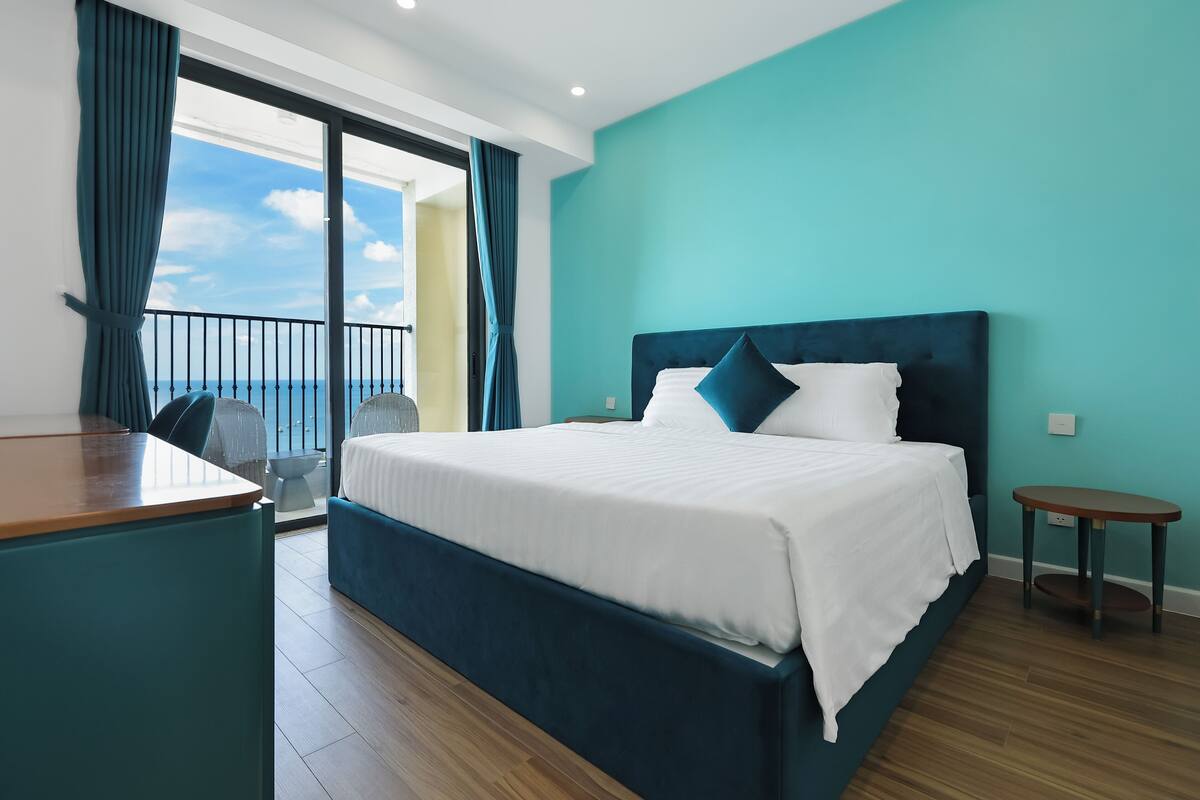 Habitación de hotel con una cama grande, un escritorio y vistas al cielo.
