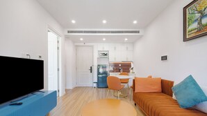 Ein modernes Wohnzimmer mit einem Flachbildfernseher, einem runden Couchtisch, einem orangefarbenen Sofa und einem Essbereich mit Tisch und Stühlen.