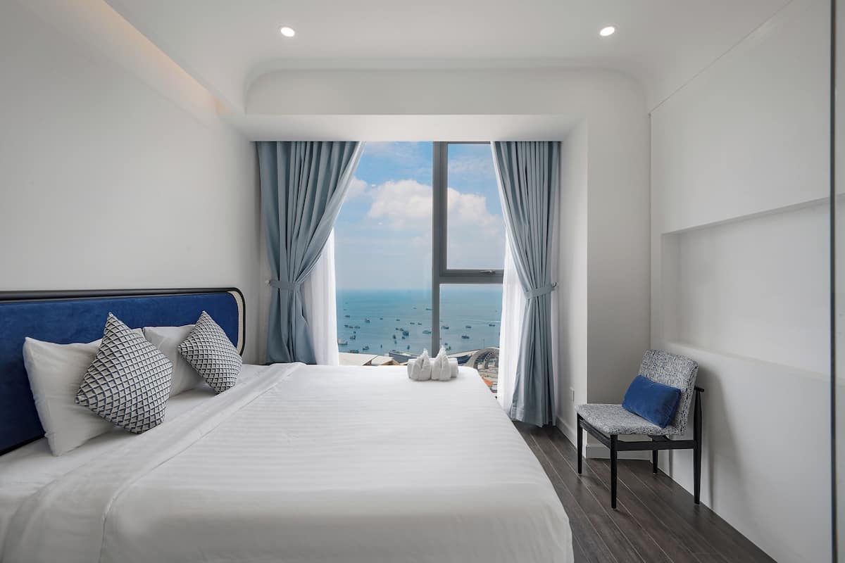 Habitación de hotel con una cama grande, una silla y vista al mar.