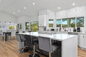 Eine moderne Küche mit einer großen Kochinsel, Barhocker und einem Essbereich mit Tisch und Stühlen.