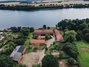 An aerial view of a large building complex with multiple structures, surrounded by greenery and a lake. - Idyllic location - vacation home for families with dogs 1 hour from Berlin on the lake. (Neuruppin)