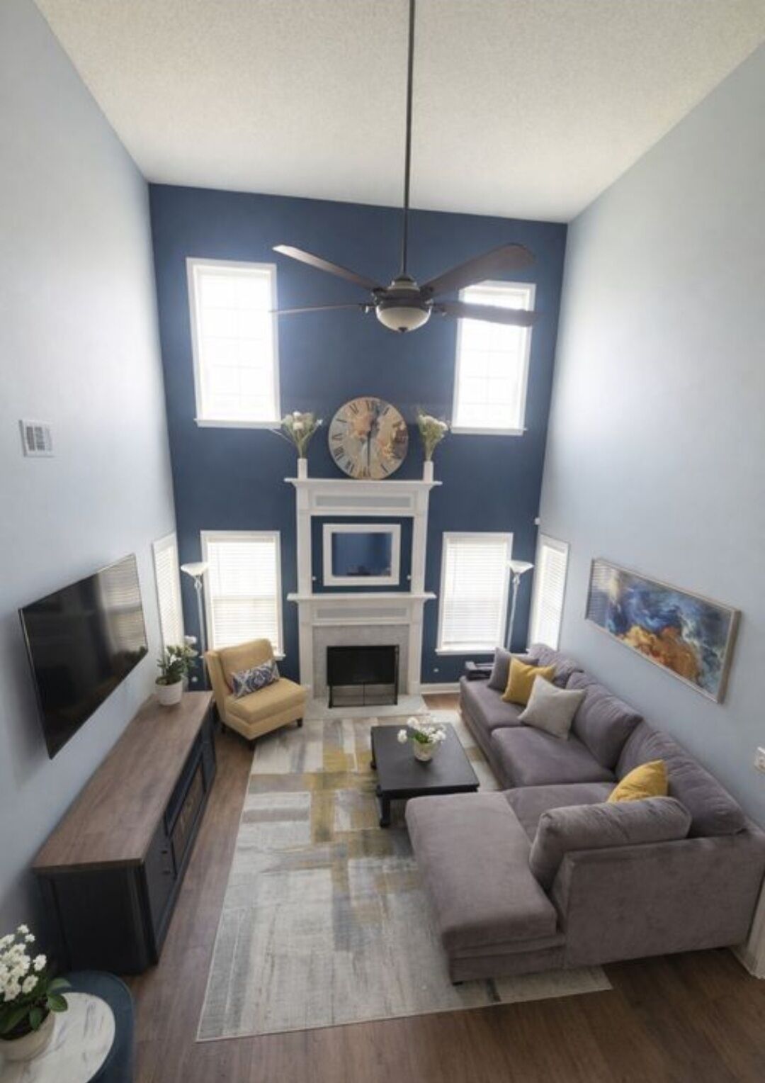 A living room with a fireplace, sofa, TV, and ceiling fan.