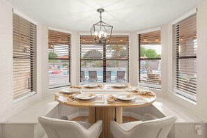A dining area with a round table, white chairs, and a central light fixture. - The Ultimate Stay & Play Retreat • 4BR • Sleeps 13 (Chandler)