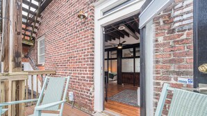 Een gevel van baksteen met een houten terras, zitplaatsen buiten en een deur naar de binnenruimte.