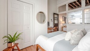 Een slaapkamer met twee bedden, een ronde spiegel, een bureau en een stoel.