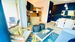 Un salon moderne comprenant un canapé, des poufs, une table basse et un coin repas avec des chaises et une table.