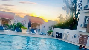 Une piscine avec des chaises longues et un bâtiment en arrière-plan.