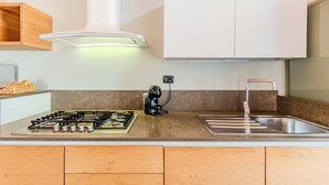 Une cuisine équipée d’une cuisinière à gaz, d’une machine à café, d’un évier et de meubles de rangement en bois.
