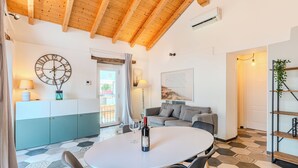 Un intérieur moderne avec une table à manger ronde, un canapé, une horloge et un coin cuisine.